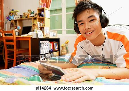 Young man listening to music, smiling at camera View Large Photo Image Picture - Young man listening to music, smiling at camera. Fotosearch