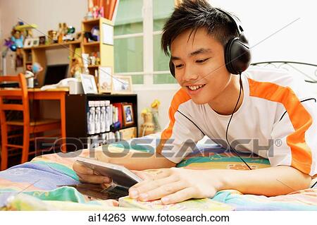 Young man listening to music, smiling View Large Photo Image Stock Image - Young man listening to music, smiling. Fotosearch