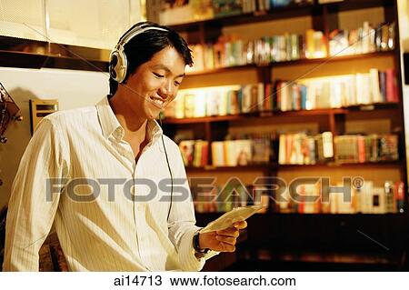 Young man listening to music, smiling, holding CD View Large Photo Image Stock Image - Young man listening to music, smiling, holding CD. Fotosearch