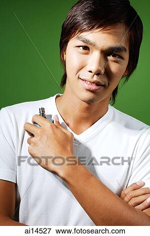 Young man looking at camera, holding bottle of perfume View Large Photo Image Stock Photo - Young man looking at camera, holding bottle of perfume. Fotosearch