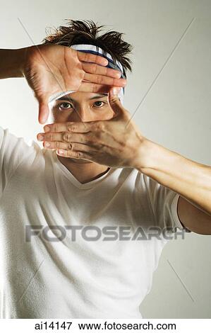 Young man looking through his hands at camera View Large Photo Image Stock Photo - Young man looking through his hands at camera. Fotosearch