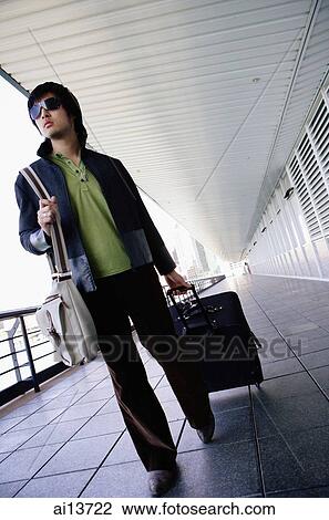 Young man pulling suitcase, walking View Large Photo Image Stock Image - Young man pulling suitcase, walking. Fotosearch