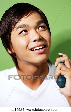 Young man spraying himself with perfume View Large Photo Image Picture - Young man spraying himself with perfume. Fotosearch