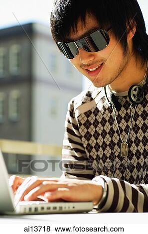 Young man using laptop, wearing sunglasses View Large Photo Image Stock Photo - Young man using laptop, wearing sunglasses. Fotosearch
