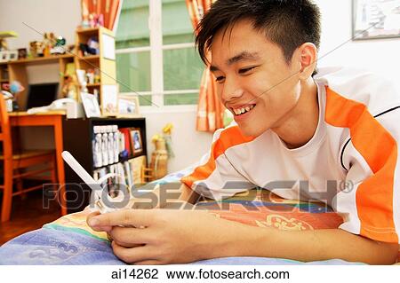 Young man using mobile phone, smiling View Large Photo Image Stock Image - Young man using mobile phone, smiling. Fotosearch