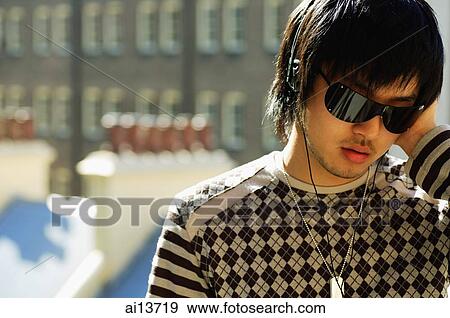 Young man wearing sunglasses and headphones View Large Photo Image Stock Photo - Young man wearing sunglasses and headphones. Fotosearch