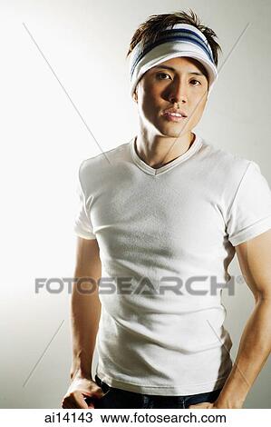 Stock Image - Young man with sun visor, looking at camera. Fotosearch