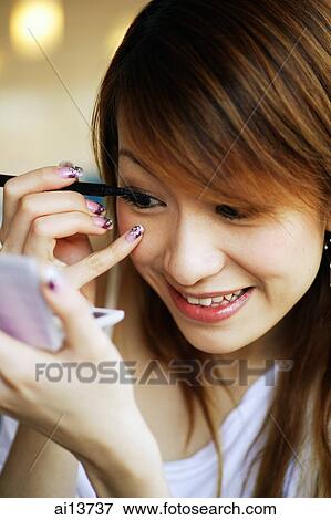 Stock Photo - Young woman applying mascara. Fotosearch