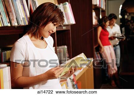 Young woman at bookstore, looking at book View Large Photo Image Stock Image - Young woman at bookstore, looking at book. Fotosearch