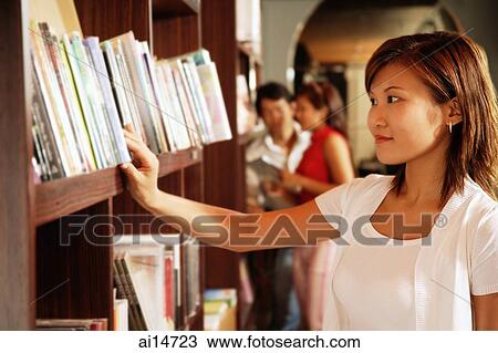Young woman at bookstore, looking at books on shelf View Large Photo Image Stock Image - Young woman at bookstore, looking at books on shelf. Fotosearch