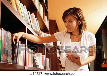 Young woman at bookstore, selecting book from shelf View Large Photo Image Stock Photo - Young woman at bookstore, selecting book from shelf. Fotosearch