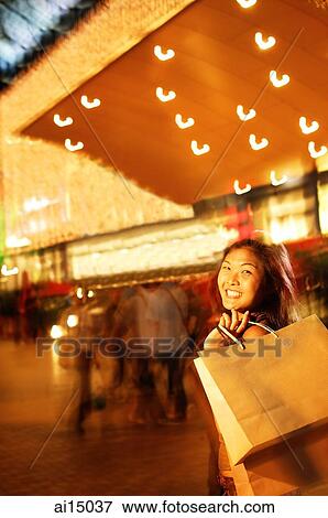 Stock Photo - Young woman, carrying shopping bag over shoulder. Fotosearch