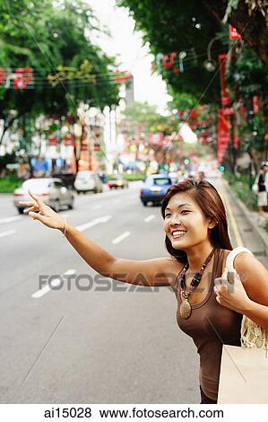 Stock Photo - Young woman, flagging a cab. Fotosearch