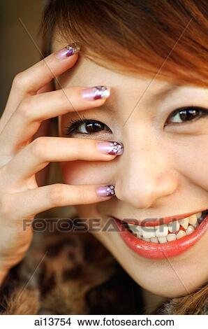Picture - Young woman, hand on face, looking at camera. Fotosearch