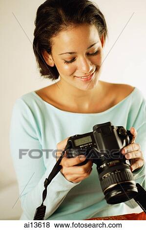 Young woman holding and looking at camera View Large Photo Image Stock Photo - Young woman holding and looking at camera. Fotosearch