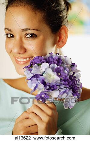 Young woman holding bouquet of flowers, looking at camera View Large Photo Image Stock Image - Young woman holding bouquet of flowers, looking at camera. Fotosearch