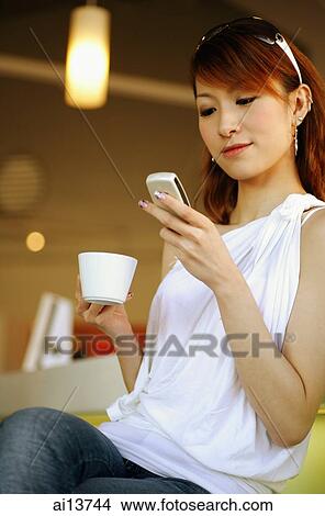 Young woman holding cup and mobile phone View Large Photo Image Picture - Young woman holding cup and mobile phone. Fotosearch