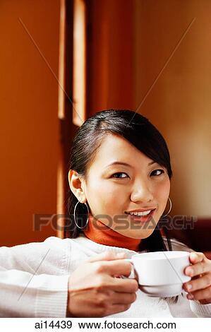 Young woman holding cup, looking at camera View Large Photo Image Stock Photo - Young woman holding cup, looking at camera. Fotosearch