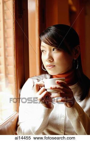 Young woman holding cup, looking out of window View Large Photo Image Stock Photography - Young woman holding cup, looking out of window. Fotosearch