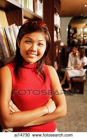 Young woman leaning on book shelf, arms crossed, looking at camera View Large Photo Image Stock Image - Young woman leaning on book shelf, arms crossed, looking at camera. Fotosearch