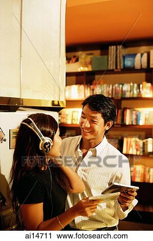 Young woman listening to CD, looking at man next to her View Large Photo Image Stock Image - Young woman listening to CD, looking at man next to her. Fotosearch
