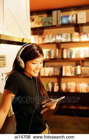Young woman listening to music, holding CD, smiling View Large Photo Image Stock Photo - Young woman listening to music, holding CD, smiling. Fotosearch