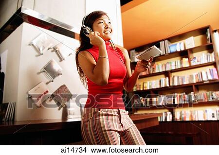 Young woman listening to music, smiling, looking away View Large Photo Image Picture - Young woman listening to music, smiling, looking away. Fotosearch