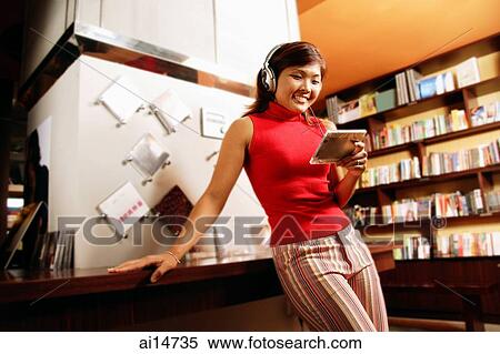 Young woman listening to music, smiling, leaning against counter View Large Photo Image Stock Photography - Young woman listening to music, smiling, leaning against counter. Fotosearch