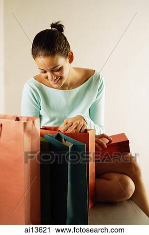 Young woman looking through shopping bags View Large Photo Image Stock Image - Young woman looking through shopping bags. Fotosearch