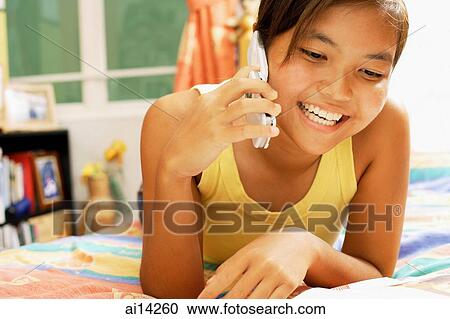 Young woman, lying on bed using mobile phone View Large Photo Image Stock Image - Young woman, lying on bed using mobile phone. Fotosearch
