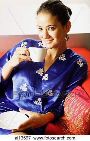 Young woman on sofa, drinking from teacup View Large Photo Image Stock Photo - Young woman on sofa, drinking from teacup. Fotosearch