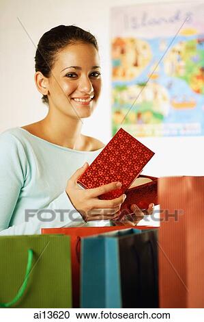 Young woman opening box, looking at camera View Large Photo Image Stock Image - Young woman opening box, looking at camera. Fotosearch