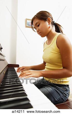 Stock Image - Young woman playing the piano, at home. Fotosearch