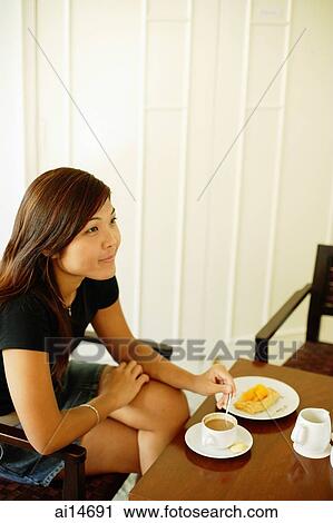 Young woman sitting, food and coffee in front of her, looking away View Large Photo Image Stock Image - Young woman sitting, food and coffee in front of her, looking away. Fotosearch