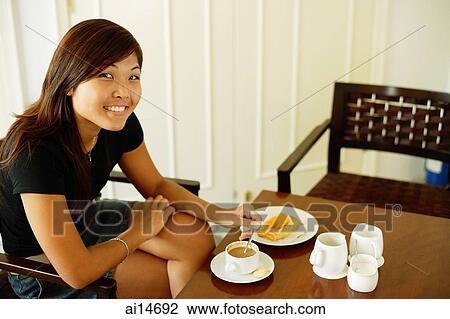 Young woman sitting, food and coffee in front of her, looking at camera View Large Photo Image Stock Image - Young woman sitting, food and coffee in front of her, looking at camera. Fotosearch