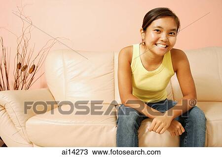 Young woman, sitting on sofa, smiling View Large Photo Image Stock Image - Young woman, sitting on sofa, smiling. Fotosearch