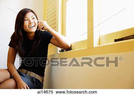 Stock Photography - Young woman sitting, using mobile phone. Fotosearch