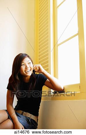 Young woman sitting, using mobile phone, portrait View Large Photo Image Stock Photograph - Young woman sitting, using mobile phone, portrait. Fotosearch