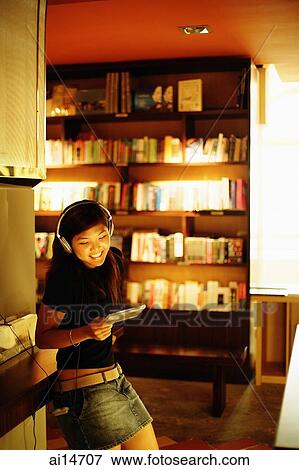 Young woman standing, listening to music, holding CD, smiling View Large Photo Image Stock Photo - Young woman standing, listening to music, holding CD, smiling. Fotosearch