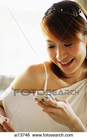 Young woman using mobile phone, smiling View Large Photo Image Stock Photograph - Young woman using mobile phone, smiling. Fotosearch