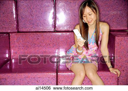 Stock Photograph - Young woman, using mobile phone, text messaging. Fotosearch