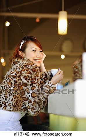 Young woman wearing fur coat, sitting at counter, looking away View Large Photo Image Stock Image - Young woman wearing fur coat, sitting at counter, looking away. Fotosearch