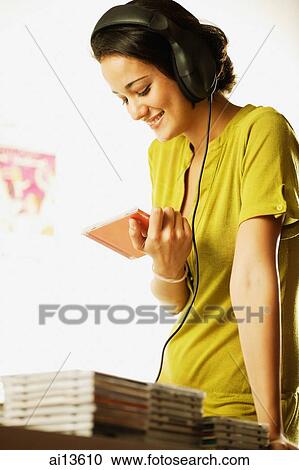 Young woman wearing headphones, holding CD case View Large Photo Image Stock Image - Young woman wearing headphones, holding CD case. Fotosearch