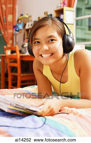 Stock Image - Young woman wearing headphones, looking at camera. Fotosearch