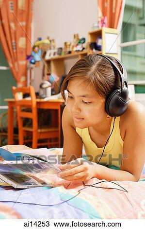 Young woman wearing headphones, looking at books View Large Photo Image Stock Image - Young woman wearing headphones, looking at books. Fotosearch