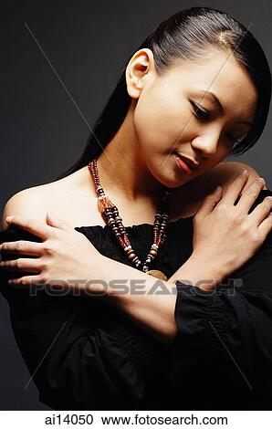 Young woman wearing necklace, arms crossed, looking down View Large Photo Image Stock Image - Young woman wearing necklace, arms crossed, looking down. Fotosearch