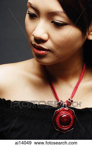 Stock Photo - Young woman wearing necklace, looking away. Fotosearch