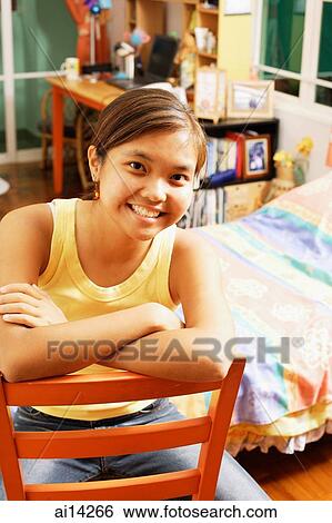 Young woman with arms folded, sitting on chair, looking at camera View Large Photo Image Stock Photograph - Young woman with arms folded, sitting on chair, looking at camera. Fotosearch
