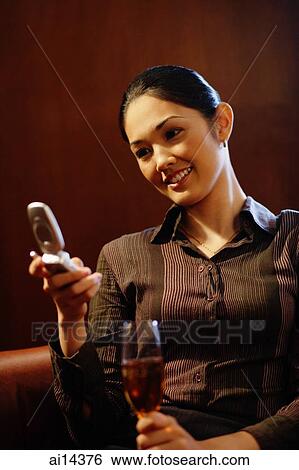 Young woman with champagne glass, using mobile phone, text messaging View Large Photo Image Stock Photograph - Young woman with champagne glass, using mobile phone, text messaging. Fotosearch