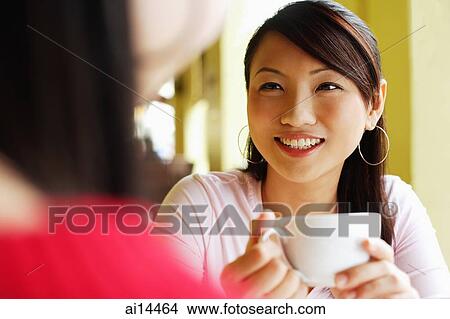 Young woman with cup in hand, smiling View Large Photo Image Picture - Young woman with cup in hand, smiling. Fotosearch